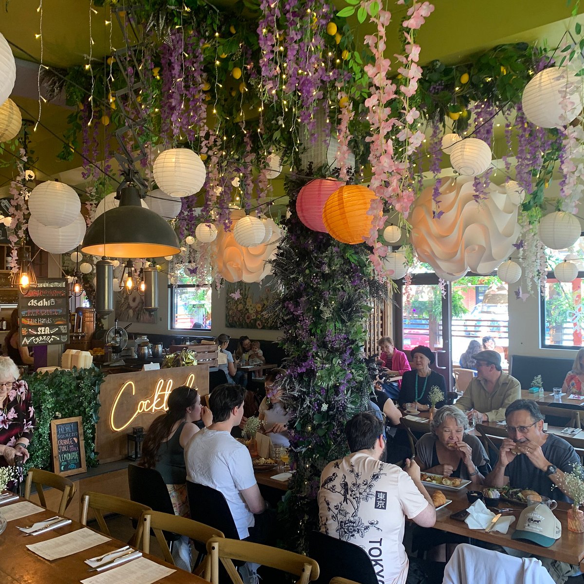 Inside Tiramisu Bistro — hanging paper lanterns, draped flowers, packed dining room